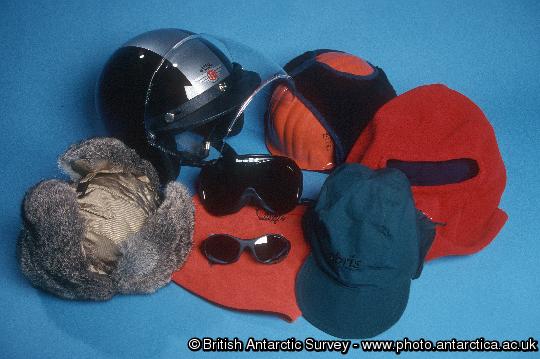 Antarctic Clothing Pictures Head gear: Upper, Skidoo Helmet, Insulated safety helmet, Fleece balaclava, lower: Fur Field Hat, Glacier Glasses and Goggles resting on Fleece Neck Tube, Field Hat.