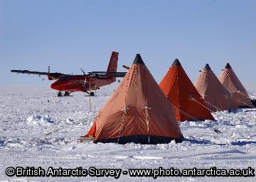 BAS Twin Otter aircraft and row of pyramid tents at an ice core drilling camp