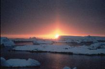 Sunset with Sun pillar across icebergs. The sun pillar is created by ice crystals in the air reflecting sunlight.